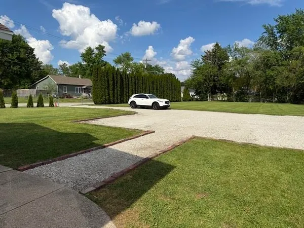 a view of a white house with a big yard and large trees