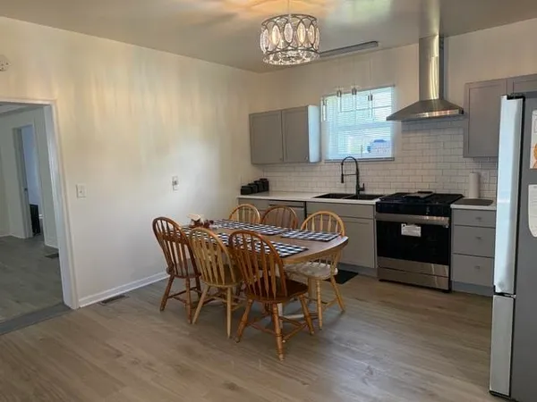 a kitchen with stainless steel appliances a table chairs and wooden floor