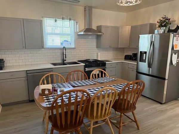 a kitchen with stainless steel appliances granite countertop a dining table chairs refrigerator and sink