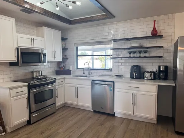 a kitchen with granite countertop stainless steel appliances a sink cabinets and wooden floor