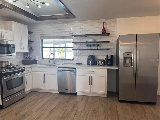 a kitchen with stainless steel appliances a sink a stove a refrigerator and cabinets