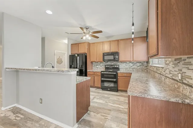 a kitchen with stainless steel appliances granite countertop a refrigerator a stove a sink and white cabinets with wooden floor