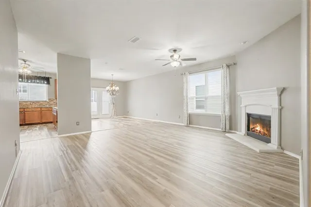a view of an empty room with wooden floor fireplace and a window