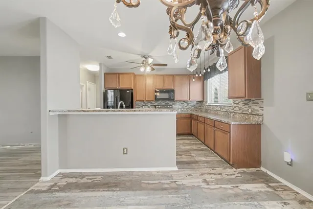 a kitchen with stainless steel appliances granite countertop a refrigerator a sink dishwasher and a oven with white cabinets