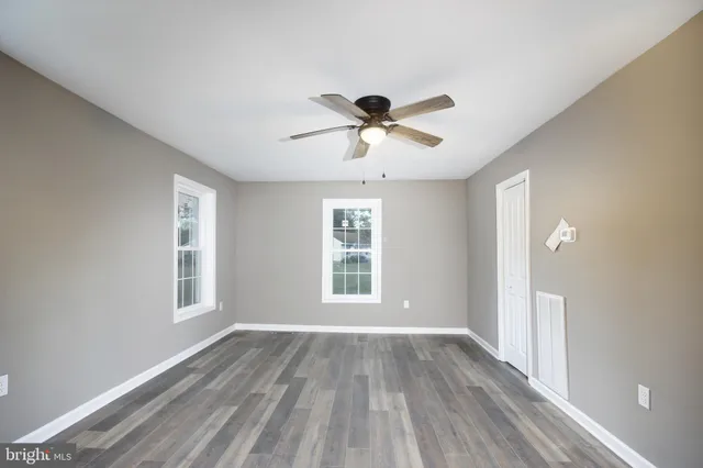 a view of empty room with wooden floor and fan
