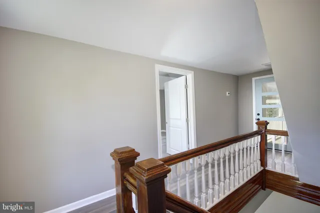 a view of a hallway with bed and wooden floor