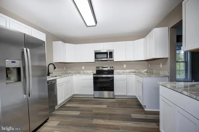 a kitchen with stainless steel appliances granite countertop a refrigerator and a stove top oven