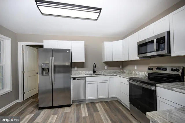 a kitchen with stainless steel appliances granite countertop a refrigerator a stove a sink and dishwasher with wooden floor