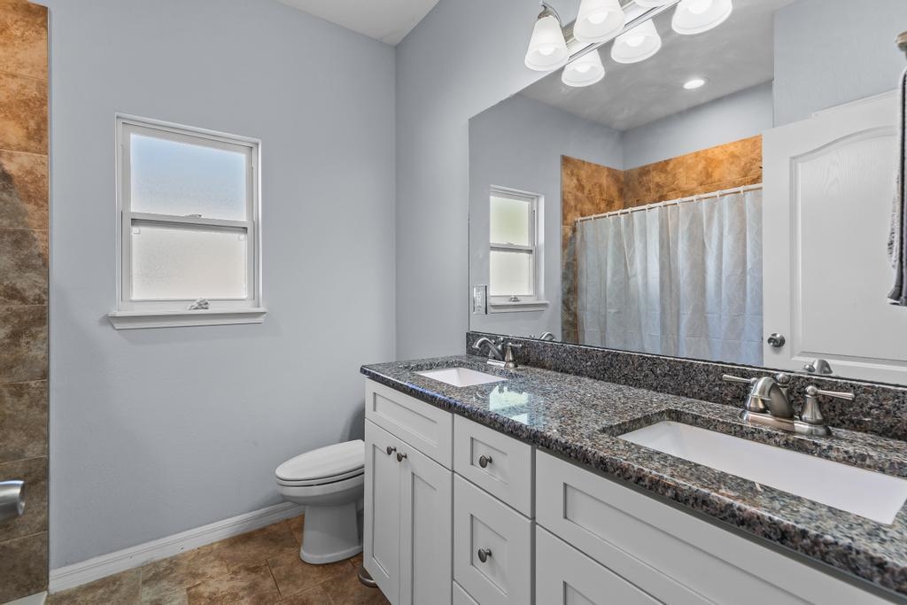 124 Dory Road St. Augustine, FL 32086 - Photo 18 of 39 a bathroom with a granite countertop sink a toilet and mirror