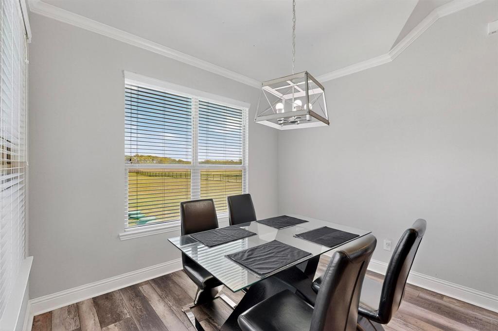 634 Gant Road Sherman, TX 75090 - Photo 18 of 40 Dining area featuring wood-finish flooring, a contemporary chandelier, crown molding, and a window with horizontal blinds