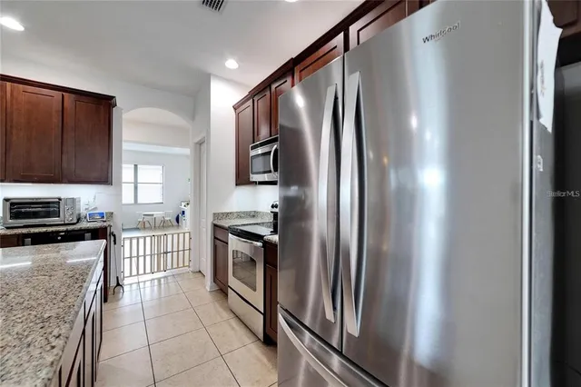 a kitchen with granite countertop a refrigerator and a stove top oven