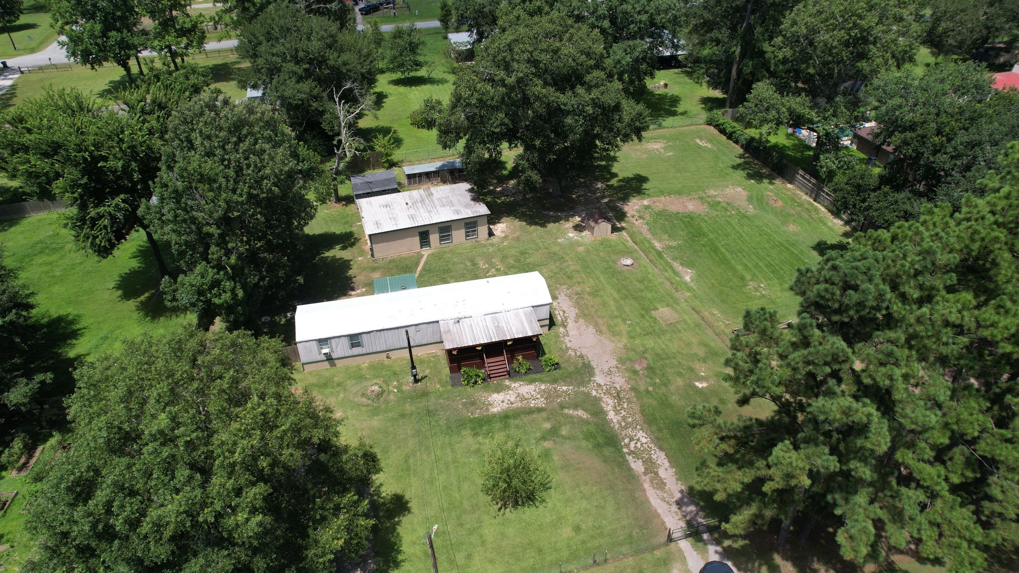 30 East Old Field Road Huffman, TX 77336 - Photo 31 of 31 The final aerial view highlights the home's peaceful setting, covered porches, detached garage, outbuildings, and expansive unrestricted acreage waiting to be enjoyed.