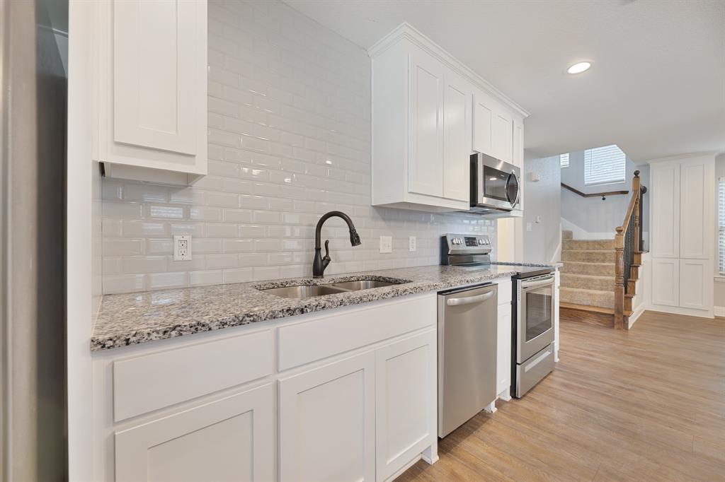 1713 Bronco Road Granbury, TX 76049 - Photo 8 of 23 Kitchen featuring white shaker-style cabinetry, a dual-basin stainless steel sink with a dark bronze faucet, granite countertops, and a subway tile backsplash