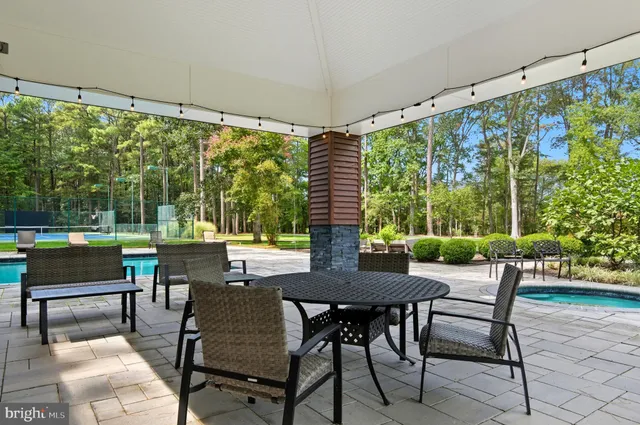 a view of pool with lawn chairs and large trees