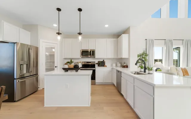 a kitchen with kitchen island a counter top space a sink stainless steel appliances and cabinets