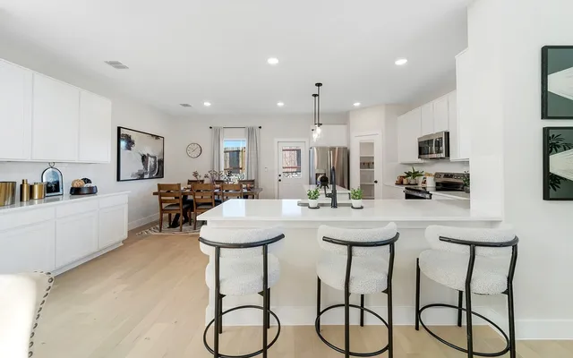a kitchen with stainless steel appliances a table and chairs in it