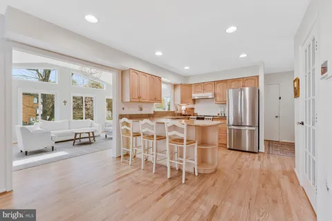 a kitchen with stainless steel appliances a refrigerator a stove a sink dishwasher and a dining table with wooden floor