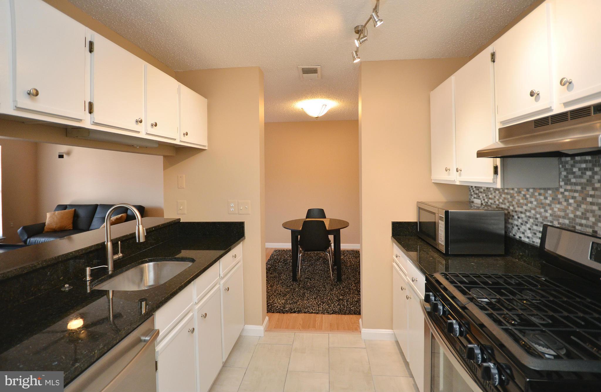 21019 Timber Ridge Terrace, Unit 302 Ashburn, VA 20147 - Photo 11 of 27 a kitchen with granite countertop a sink stove and cabinets