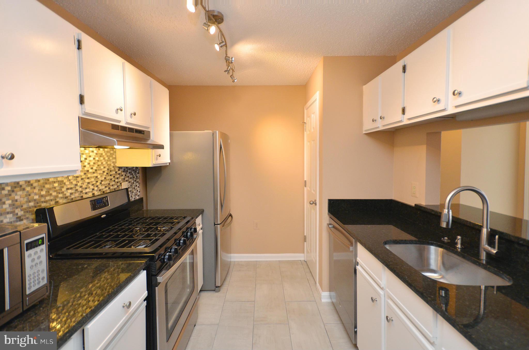 21019 Timber Ridge Terrace, Unit 302 Ashburn, VA 20147 - Photo 12 of 27 a kitchen with granite countertop a sink stainless steel appliances and cabinets