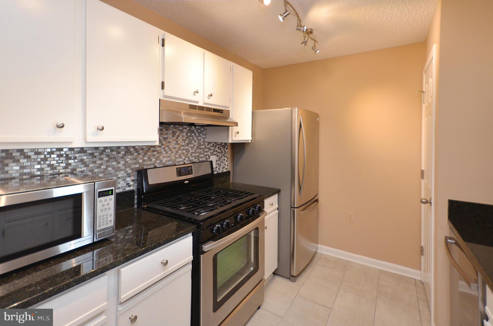 21019 Timber Ridge Terrace, Unit 302 Ashburn, VA 20147 - Photo 13 of 27 a kitchen with stainless steel appliances granite countertop a stove a refrigerator and a microwave