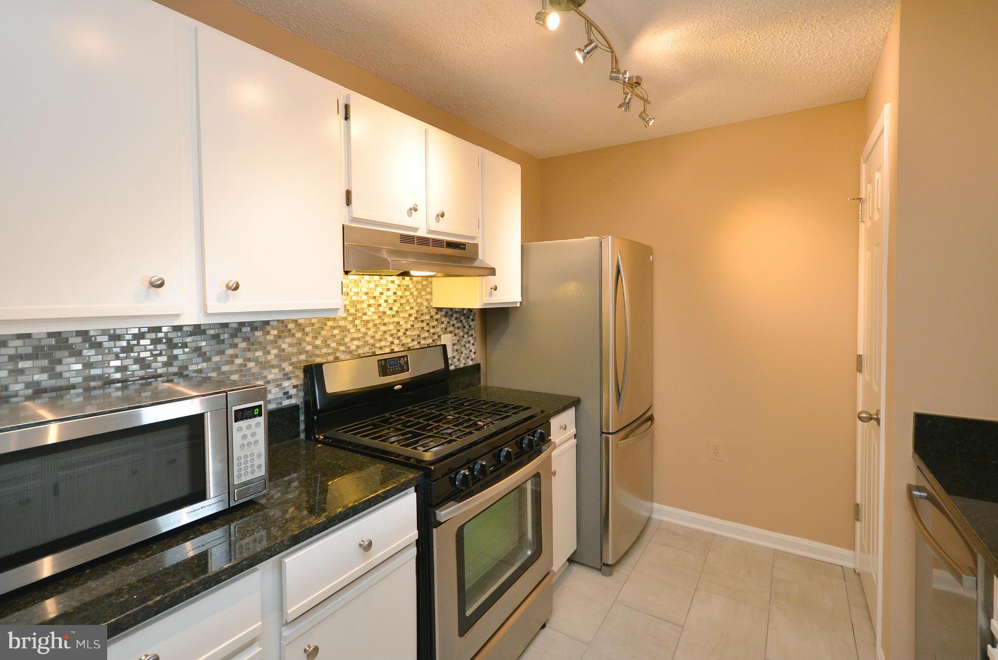 21019 Timber Ridge Terrace, Unit 302 Ashburn, VA 20147 - Photo 14 of 27 a kitchen with stainless steel appliances granite countertop a stove a refrigerator and a microwave