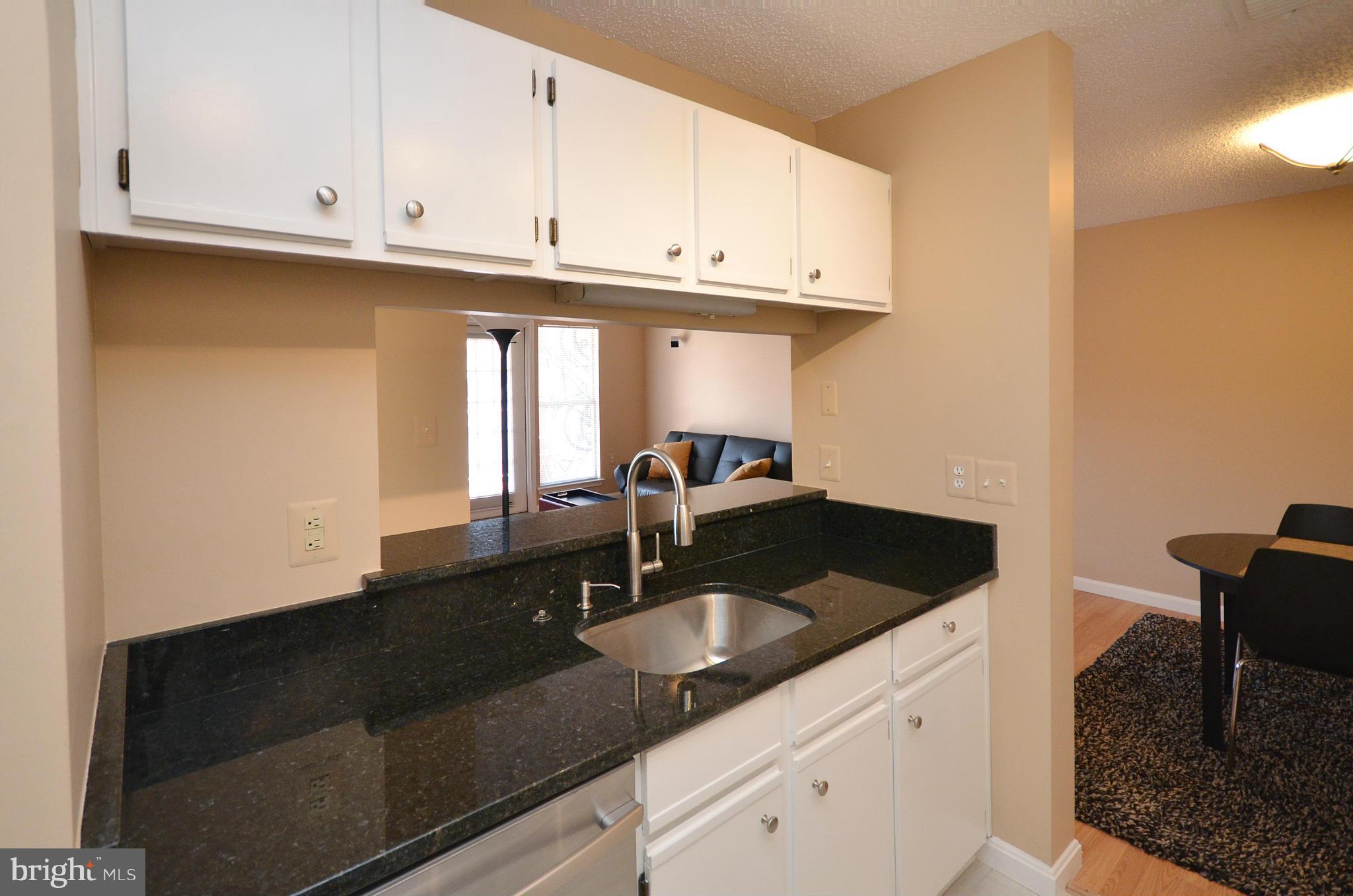 21019 Timber Ridge Terrace, Unit 302 Ashburn, VA 20147 - Photo 15 of 27 a kitchen with granite countertop a sink a stove and cabinets