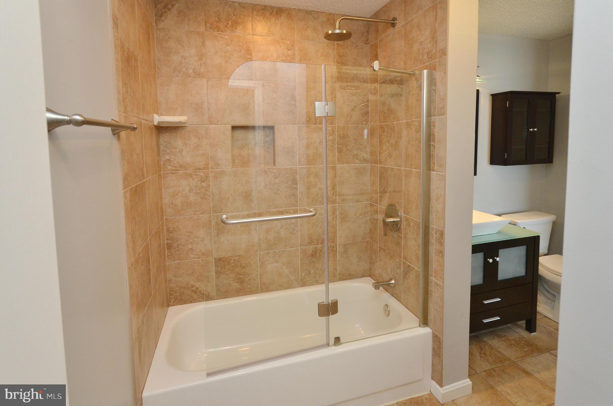 21019 Timber Ridge Terrace, Unit 302 Ashburn, VA 20147 - Photo 20 of 27 a bathroom with a bathtub and a shower