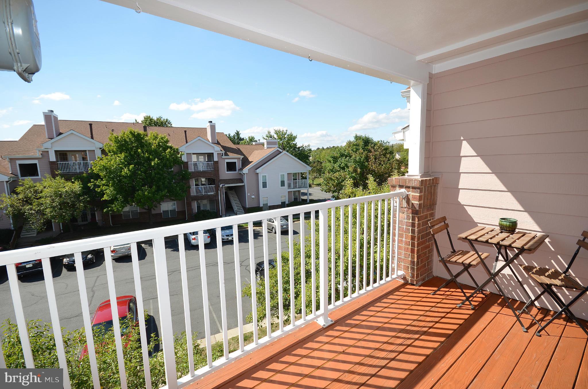 21019 Timber Ridge Terrace, Unit 302 Ashburn, VA 20147 - Photo 4 of 27 a balcony with wooden floor and city view