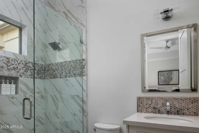 a bathroom with a granite countertop sink a toilet and shower