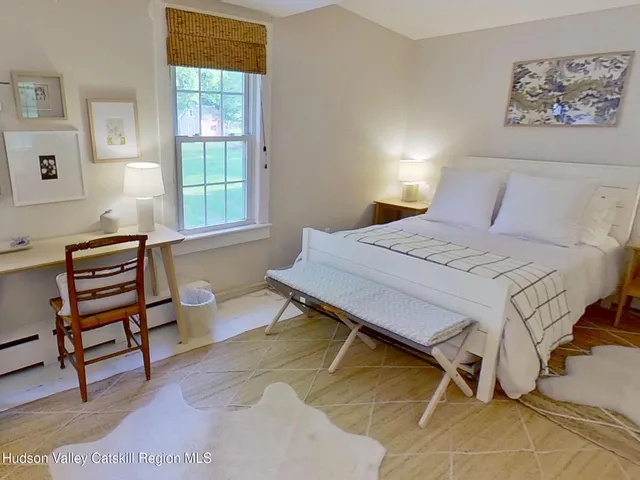 a bedroom with a bed and a potted plant on the dresser