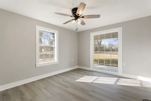 a view of an empty room with a window and wooden floor