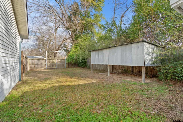 a backyard of a house with large trees and barbeque oven