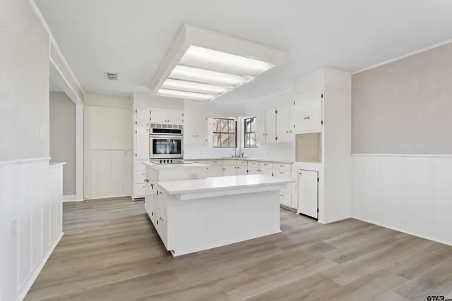 a large white kitchen with kitchen island a sink and a stove top oven