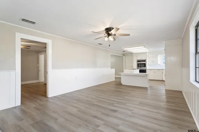 a view of empty room with wooden floor and ceiling fan