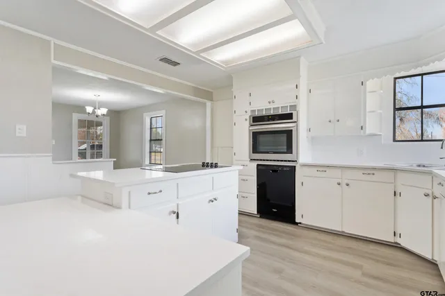 a large white kitchen with granite countertop a stove top oven a sink and dishwasher