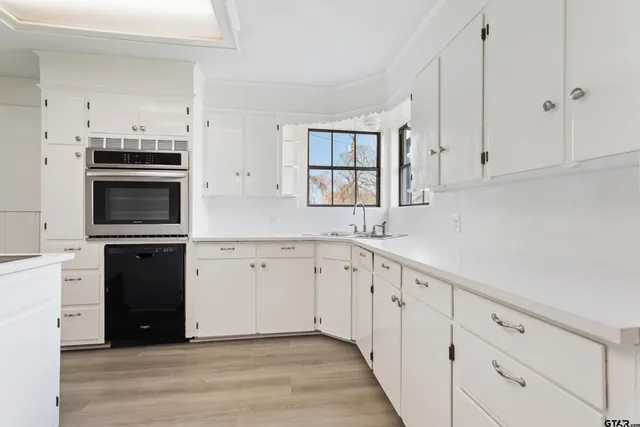 a kitchen with granite countertop white cabinets and stainless steel appliances