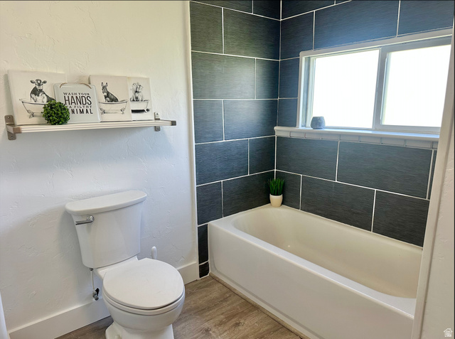 1050 West 100 North Provo, UT 84601 - Photo 6 of 16 Bathtub with dark grey subway tile surround, integrated window, and wood-finish flooring