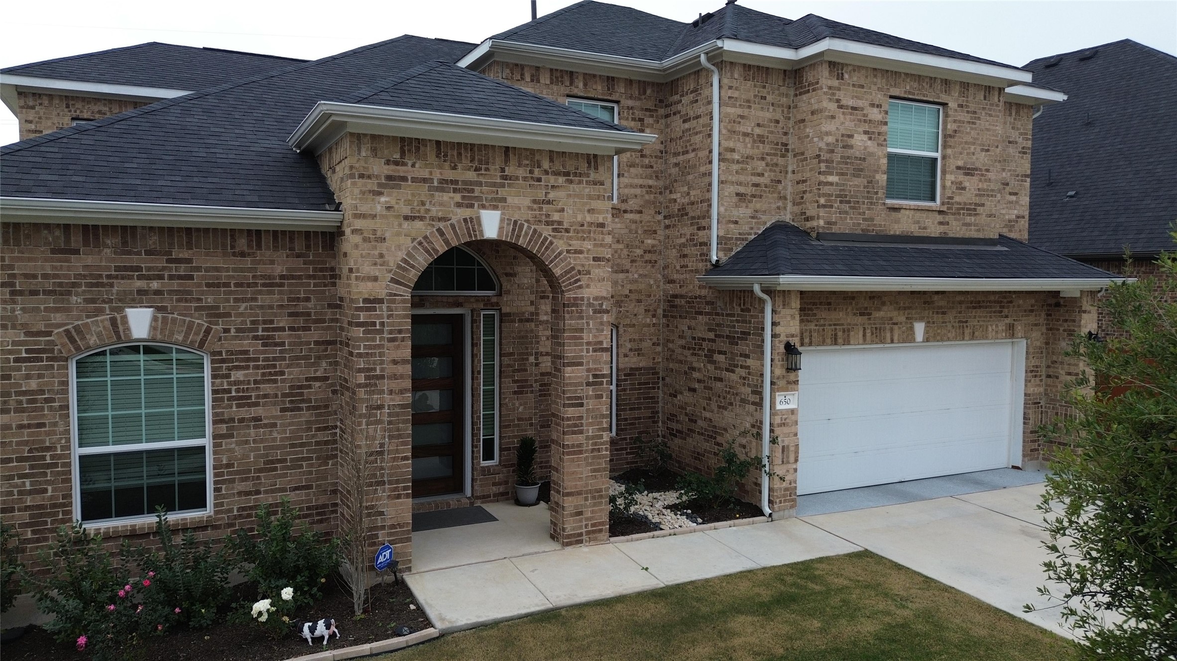 650 Wild Pecan Loop Buda, TX 78610 - Photo 2 of 28 View of front of house with brick siding, a shingled roof, and driveway