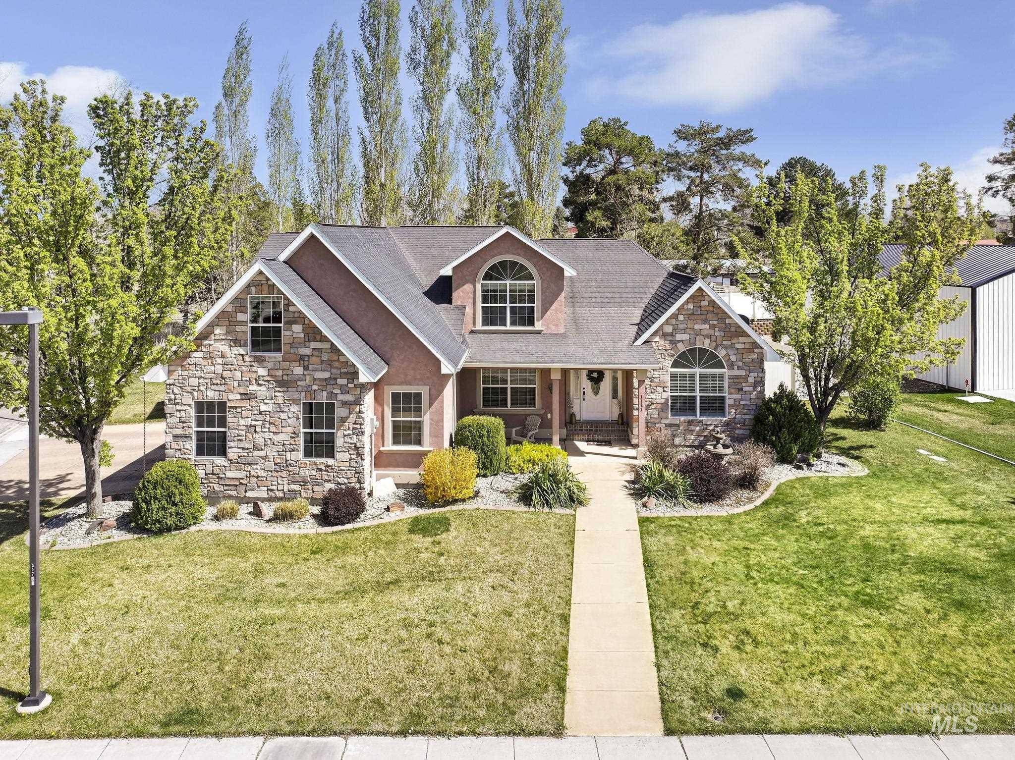 View of front facade featuring stone siding, a porch, a front lawn, and a shingled roof