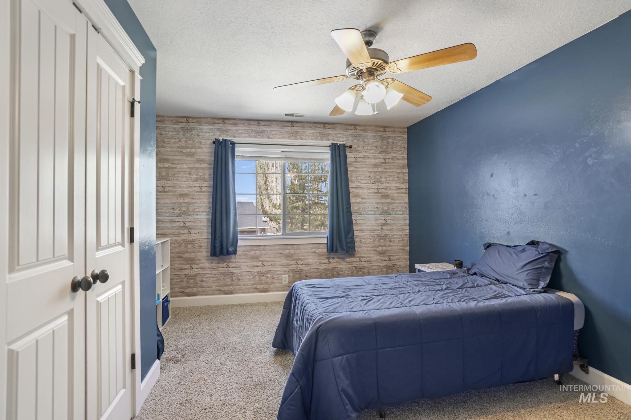 1111 Cole Street Kimberly, ID 83341 - Photo 30 of 46 Carpeted bedroom featuring a closet, ceiling fan, a textured ceiling, wooden walls, and an accent wall