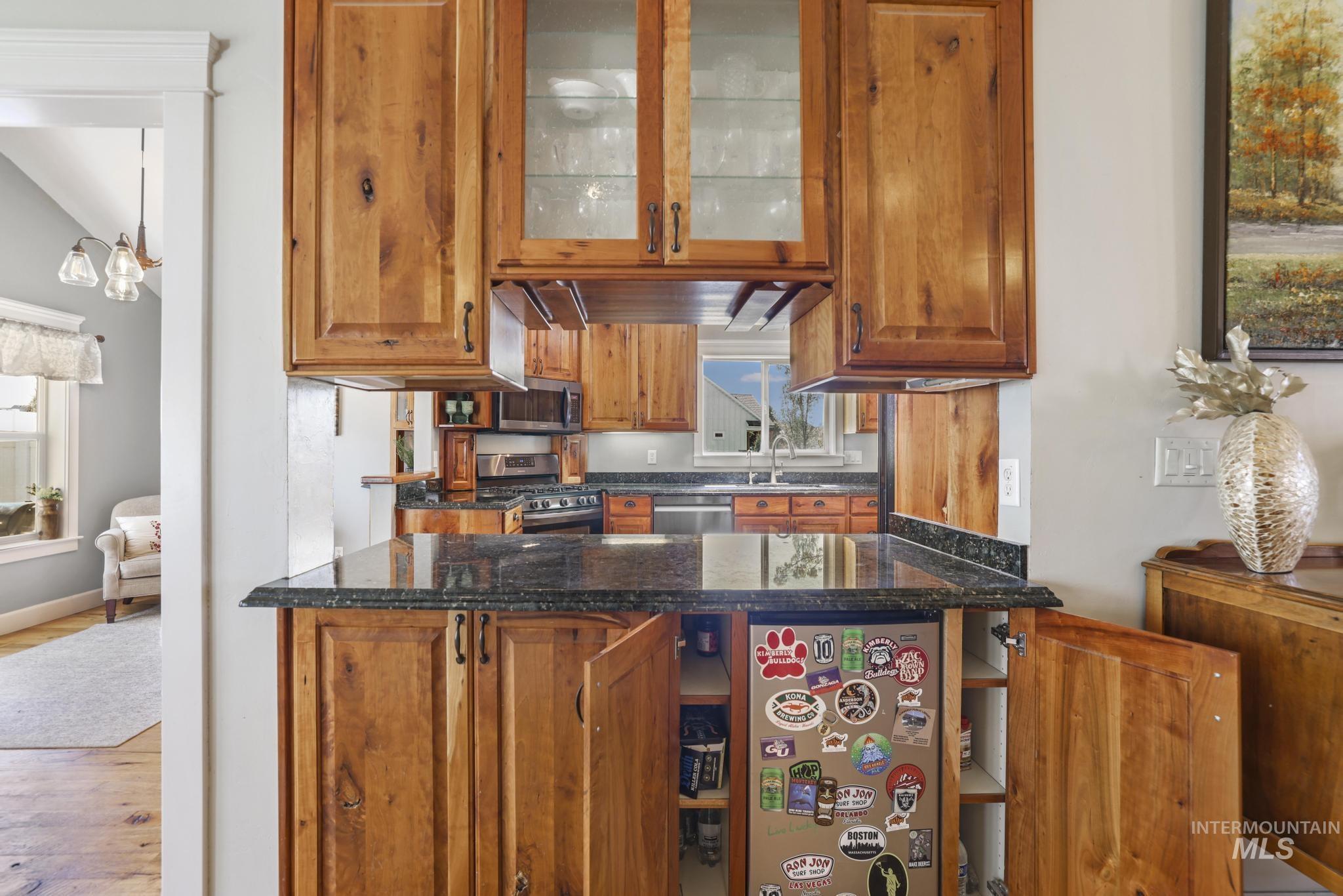 1111 Cole Street Kimberly, ID 83341 - Photo 9 of 46 Kitchen with wood finish cabinets, stainless steel appliances, glass fronted cabinets, dark stone countertops, and light wood finished floors