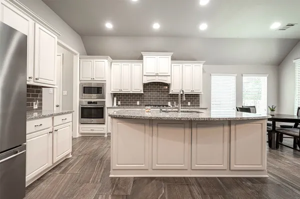 a kitchen with stainless steel appliances granite countertop a stove a sink cabinets and a refrigerator