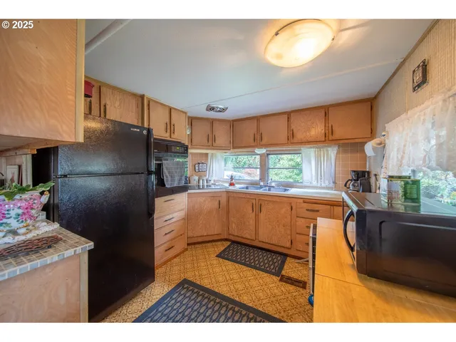 a kitchen with stainless steel appliances granite countertop a refrigerator a sink a stove a dining table and chairs with wooden floor