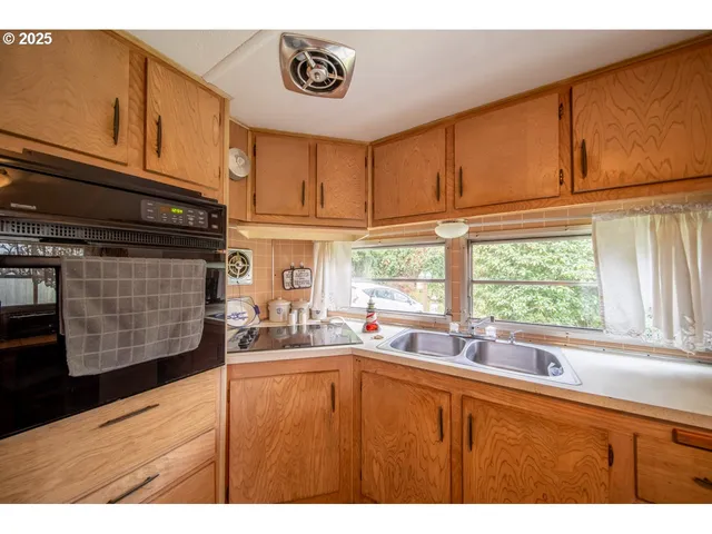 a kitchen with stainless steel appliances kitchen island wooden cabinets a window and a sink