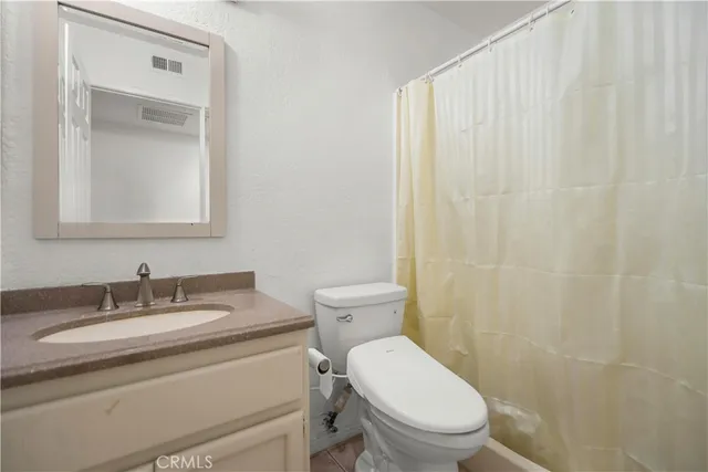 a bathroom with a granite countertop toilet a sink a mirror and a shower