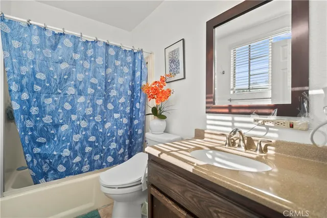 a bathroom with a granite countertop sink and a toilet
