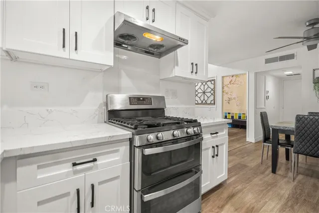 a kitchen with stainless steel appliances a stove and white cabinets