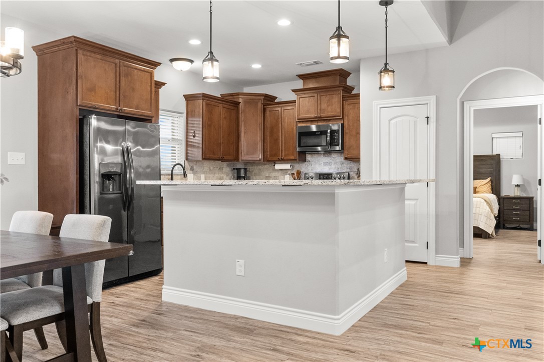 314 Blue Jay Loop Victoria, TX 77905 - Photo 8 of 27 a kitchen with stainless steel appliances kitchen island granite countertop a refrigerator a stove and a wooden floors