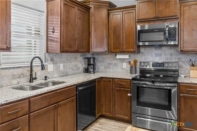 a kitchen with stainless steel appliances granite countertop a sink stove and microwave