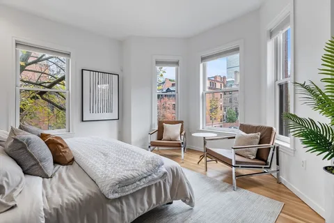 a bedroom with a bed and large windows